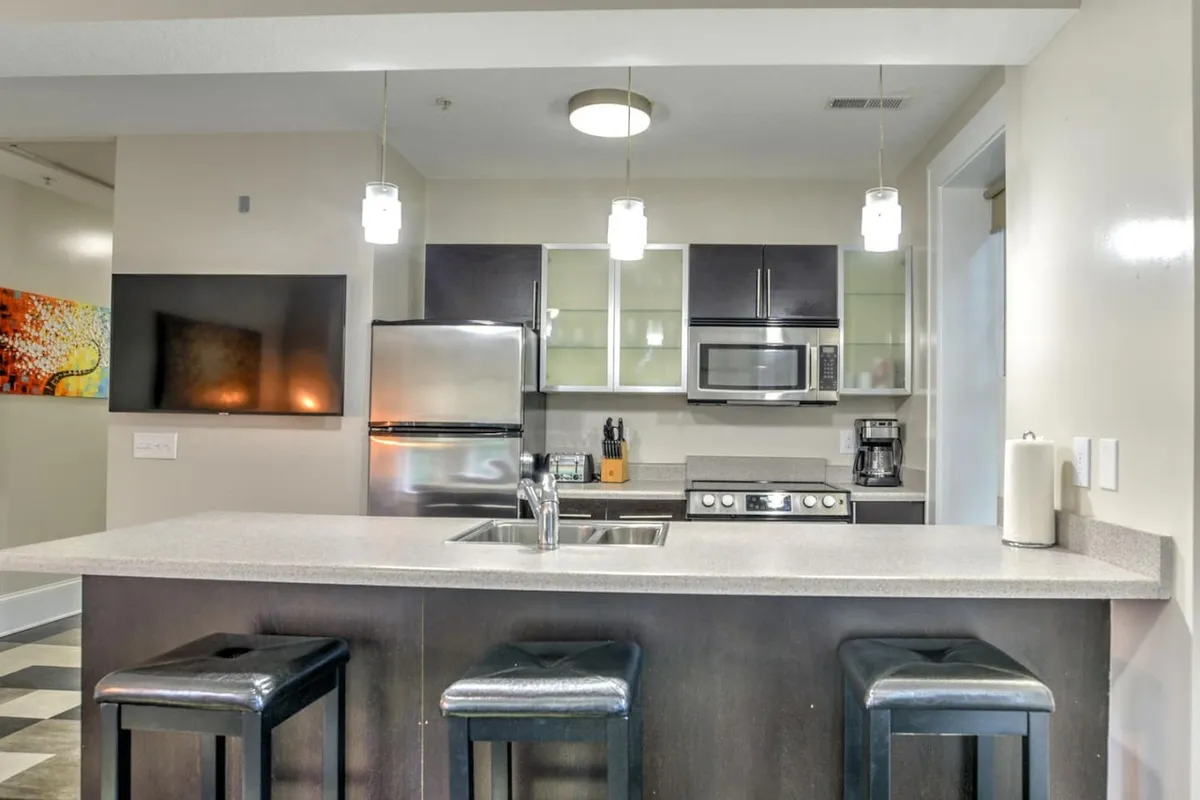 An alternate angle of the open kitchen and dining area, featuring the kitchen island with stools, stylish appliances, and vibrant wall art. The view highlights the seamless connection between cooking, dining, and social areas, creating a warm, interactive environment.